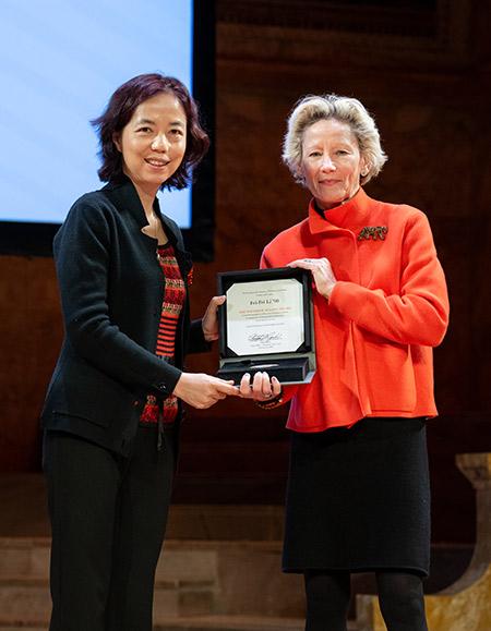 Fei-Fei Lee accepts the Woodrow Wilson Award from Weezie Sams on the stage of Richardson Auditorium